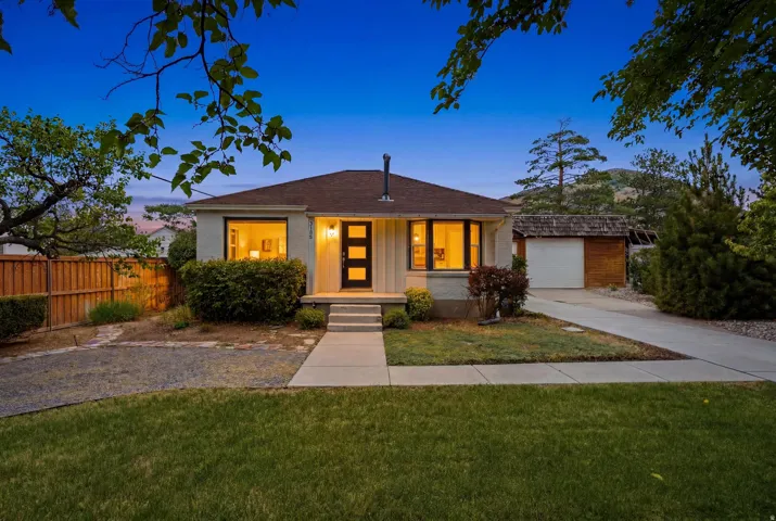 Single-story stucco residence featuring a brown shingle roof, a modern black entry door, and prominent bay windows