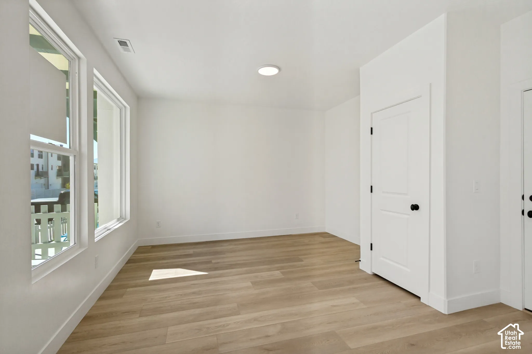 White walls with large windows, wood-finish flooring, recessed ceiling light, and white paneled doors