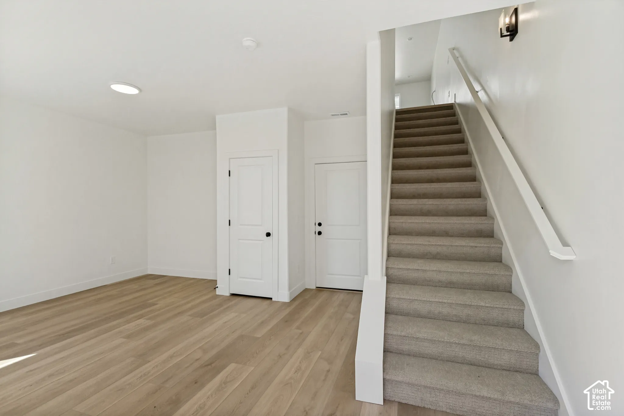 Light wood-finish flooring with white walls and trim