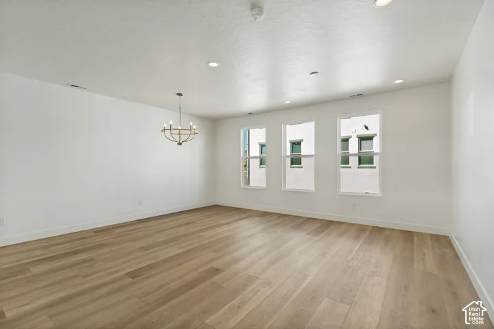 Recessed ceiling lights, wood-finish flooring, contemporary chandelier, three large windows, white painted walls