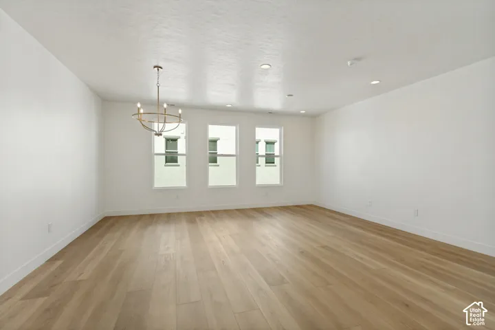 Spacious room featuring light wood-finish flooring, recessed lighting, and a modern chandelier