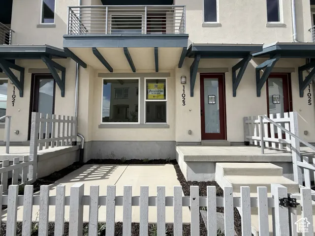 Stucco exterior with contemporary architectural details, including a second-story balcony with metal railings