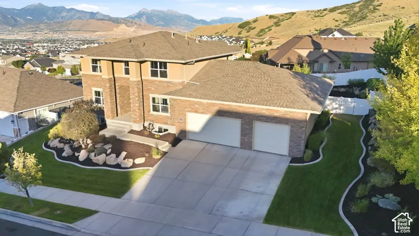 Brick and stucco exterior residence featuring a two-car garage, concrete driveway, and tiered landscaping