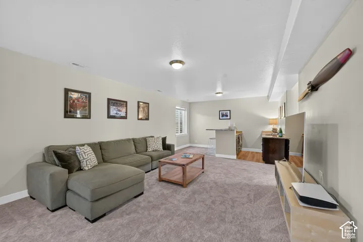 Spacious room featuring neutral carpeting, recessed lighting, and a built-in wet bar with a countertop