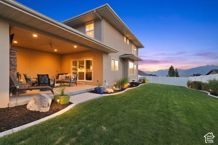 Expansive backyard featuring a covered patio with recessed lighting and a stone-clad pillar