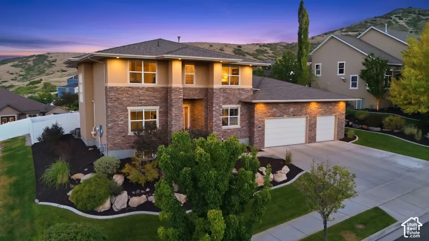Multi-level exterior featuring stone and stucco finishes, a two-car garage, and a concrete driveway