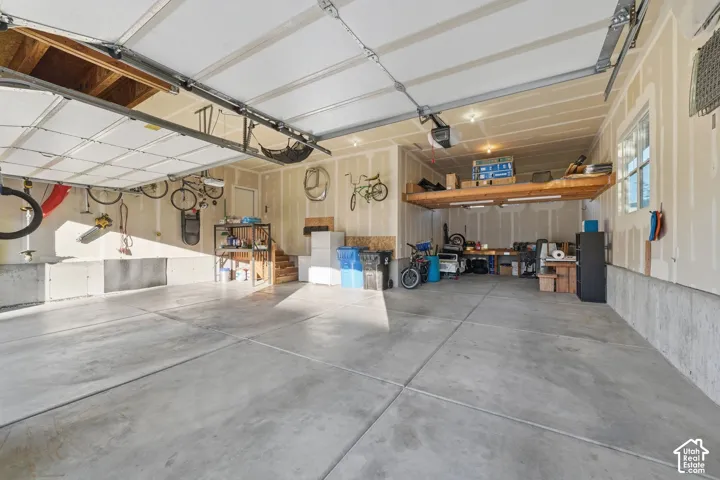 Spacious garage with concrete flooring, overhead storage platform, and an insulated garage door