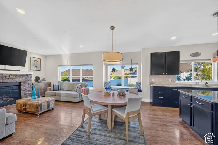 Open concept living area featuring wood-finish flooring, a stacked stone fireplace, and recessed lighting