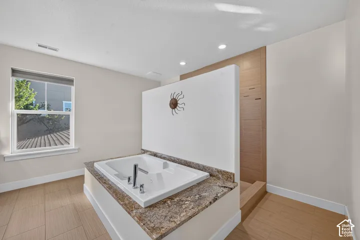 Built-in soaking tub with a stone-finish surround and polished chrome fixtures