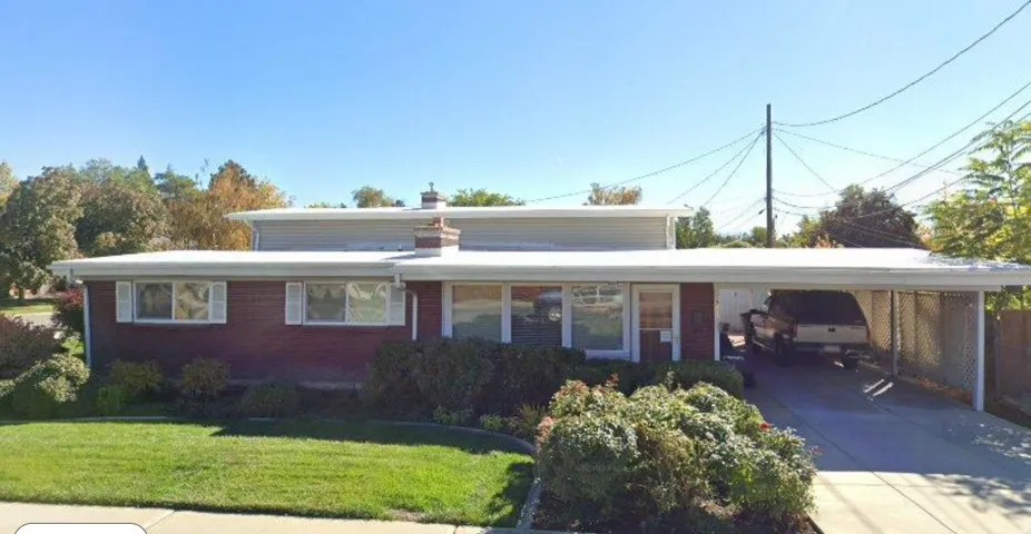 Brick exterior with white trim, featuring a manicured front lawn and established landscaping