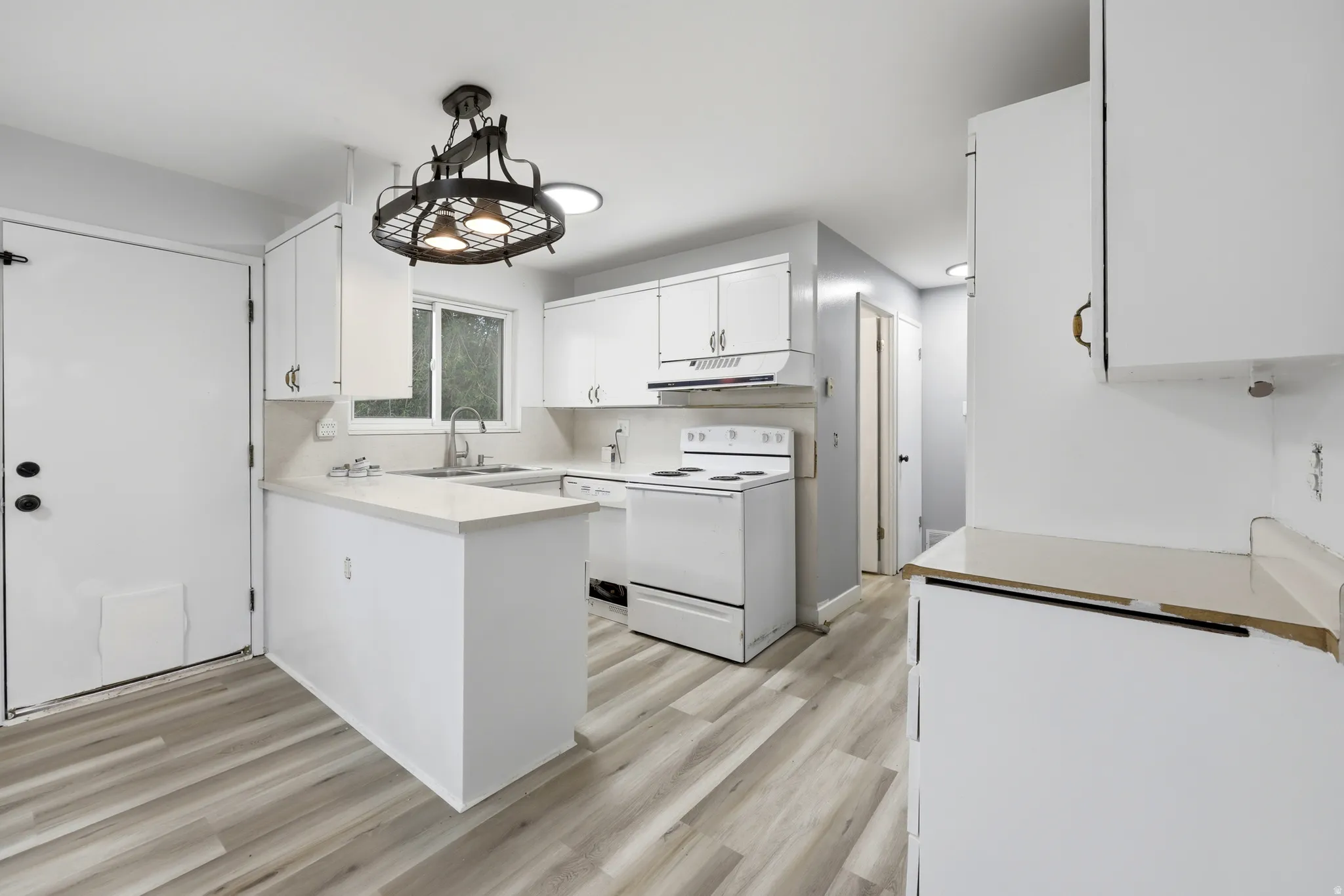 Kitchen featuring wood-finish flooring and white cabinetry