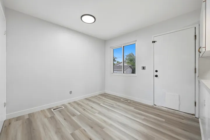 Spacious room featuring light wood-finish flooring, white walls, and a recessed ceiling light fixture