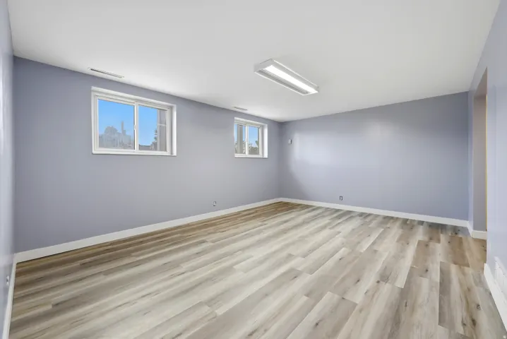 Spacious room featuring wood-finish flooring, light blue walls, and white trim
