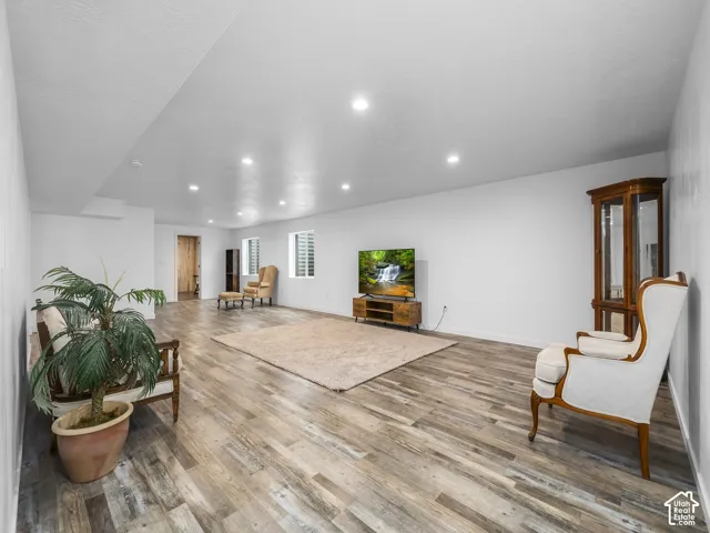 Spacious room featuring wood-finish flooring, recessed lighting, and white walls