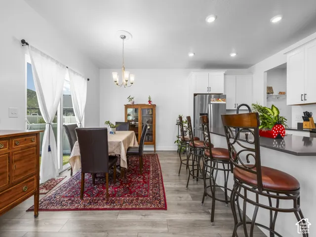 Open-concept dining area with wood-finish flooring, recessed lighting, and a chandelier