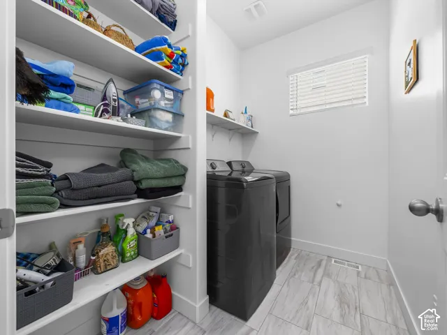 Dedicated laundry space featuring a window with blinds, tile flooring, and integrated wall shelving