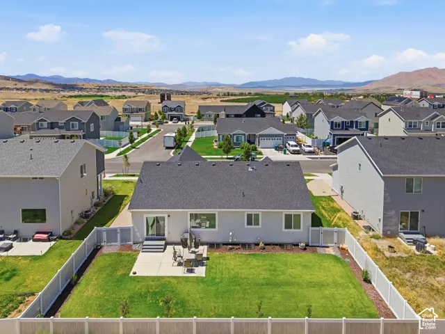 Rear exterior featuring a spacious lawn, concrete patio, and a privacy fence