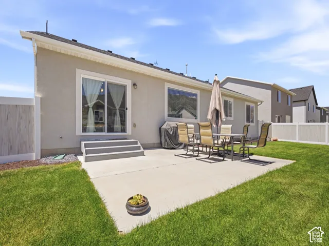Expansive backyard featuring a manicured lawn, a large concrete patio, and privacy fencing
