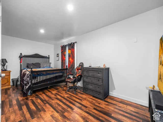 Spacious room featuring wood-finish flooring, white walls, and a window with dark curtains