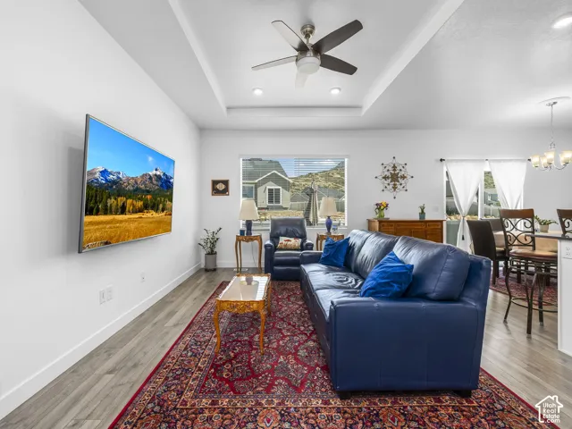Open-concept living area with tray ceiling, recessed lighting, and a ceiling fan
