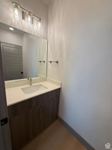 Vanity with an integrated sink, light-toned countertop, and wood-finish cabinetry