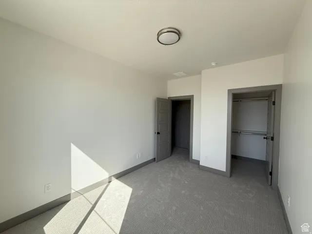 Carpeted room featuring a ceiling-mounted light fixture, white walls, and contrasting gray trim