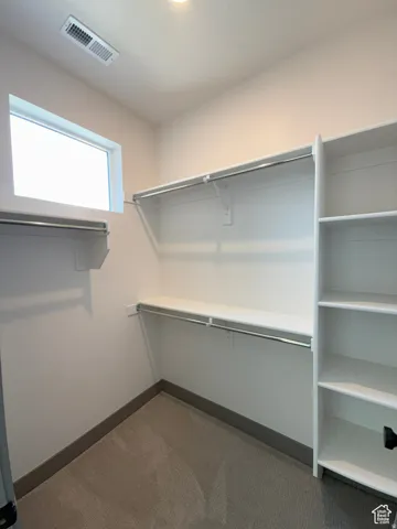 Walk-in closet featuring built-in shelving, hanging rods, and a window