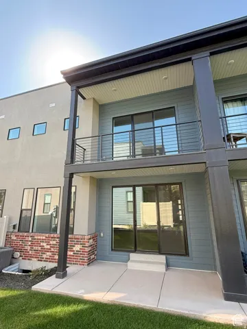 Rear exterior featuring a ground-level patio and a second-story balcony with metal railings