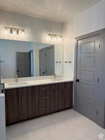 Dual vanity featuring a white countertop with integrated sinks, brushed nickel faucets, and wood-finish cabinetry