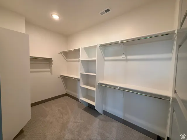 Expansive walk-in closet featuring built-in shelving, multiple hanging rods, and recessed ceiling lighting