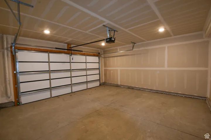Spacious garage featuring a sectional overhead door, automatic opener, concrete flooring, and recessed ceiling lighting