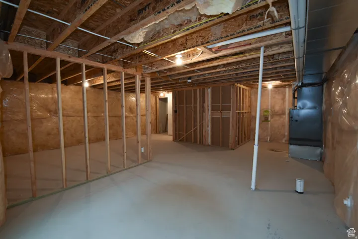 Unfinished basement with exposed ceiling joists and concrete flooring