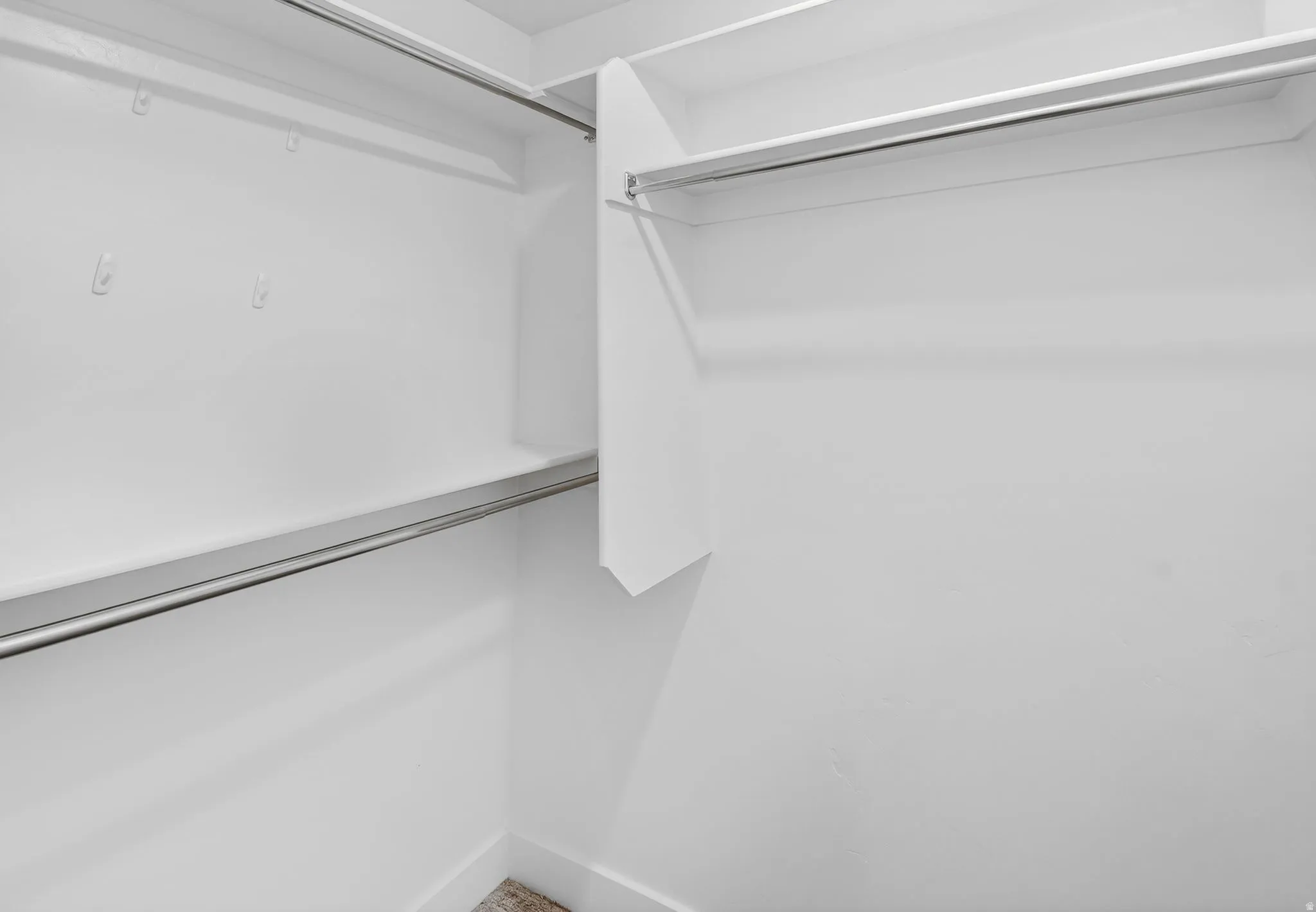 Walk-in closet with white shelving and chrome hanging rods