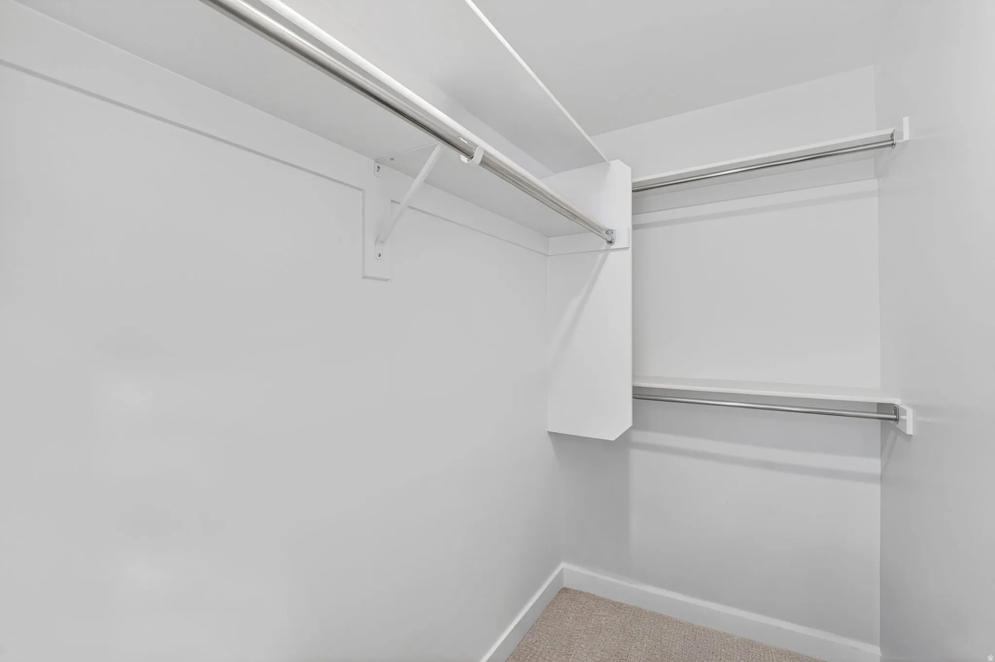 Walk-in closet featuring white shelving and chrome hanging rods