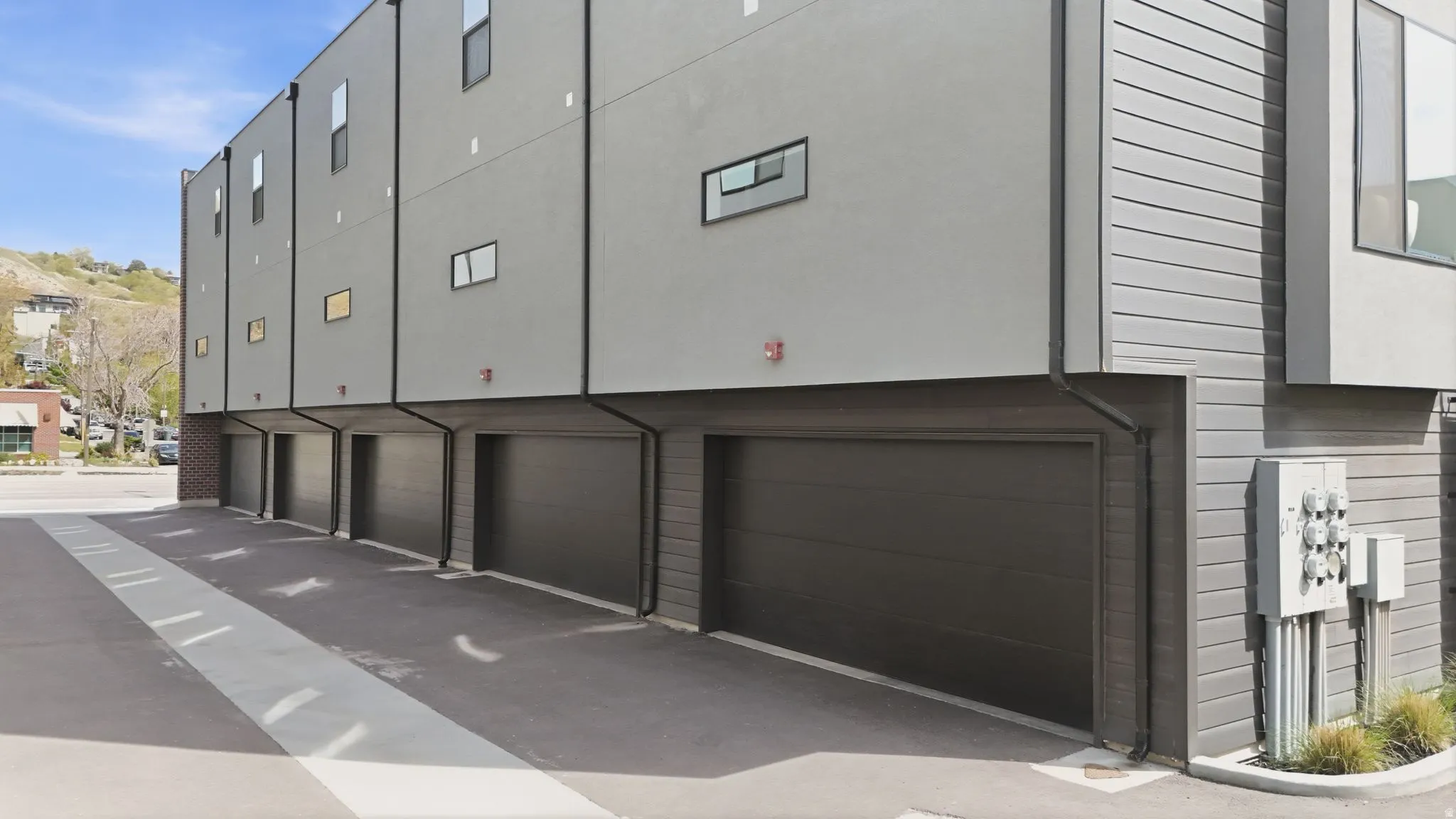 Modern multi-story building featuring individual garage access and a smooth stucco facade