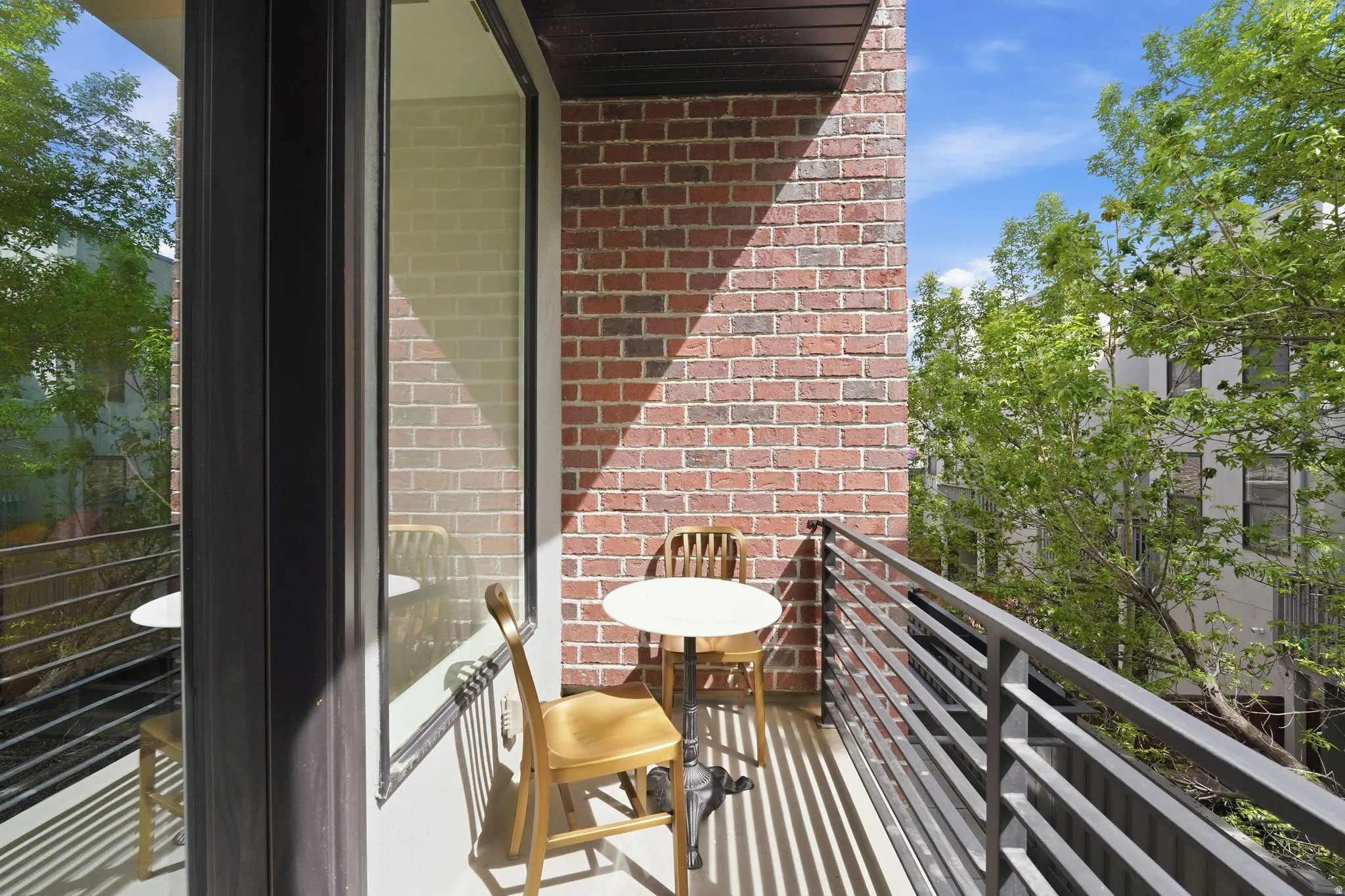 Outdoor balcony featuring a red brick wall, metal railings, and a large sliding glass door