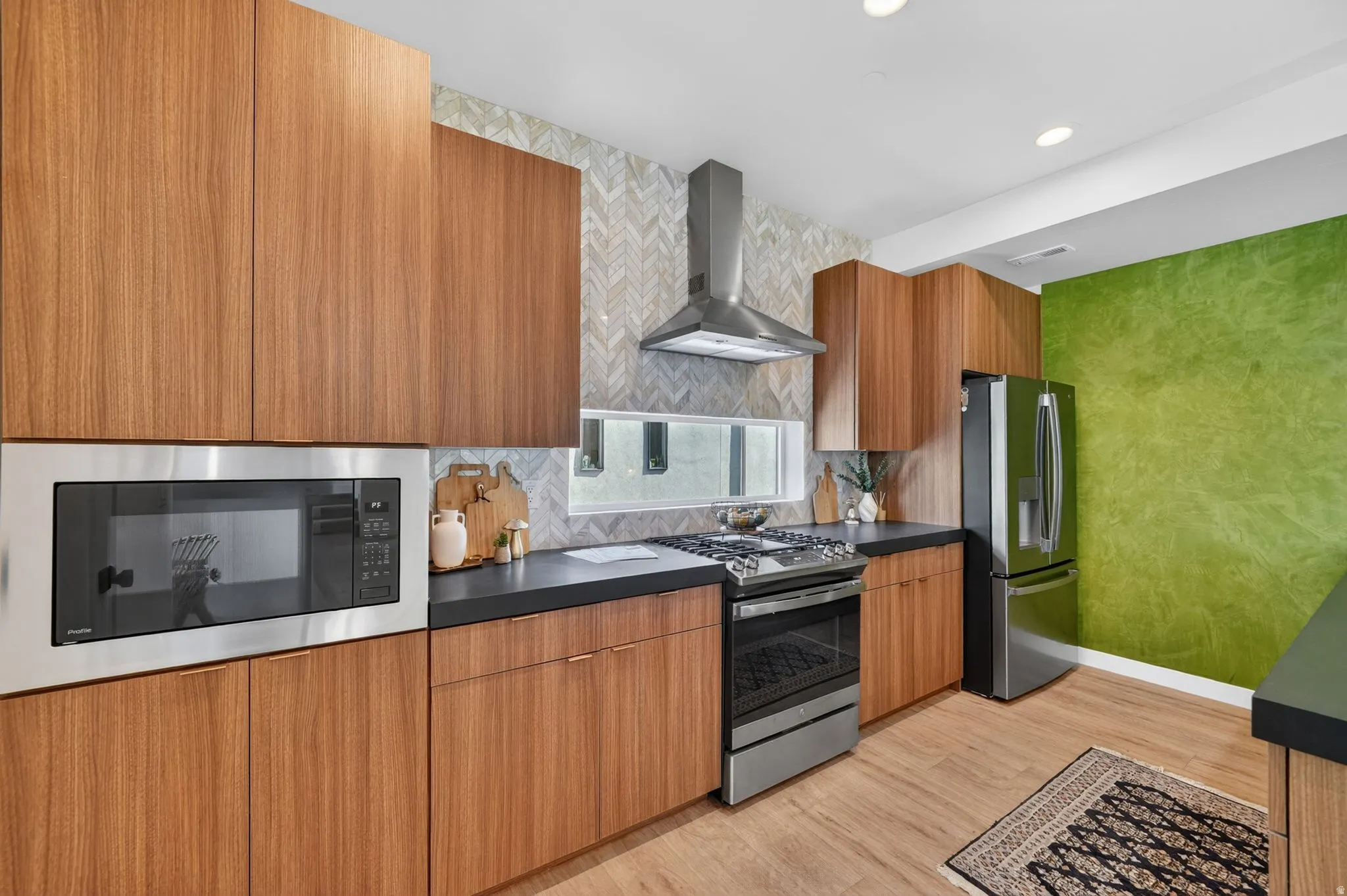 Modern kitchen featuring wood-finish cabinetry, dark countertops, and a stainless steel appliance suite