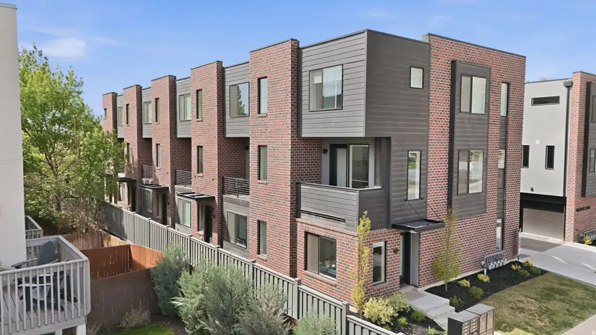 Contemporary multi-level townhome featuring a brick and dark-toned siding exterior
