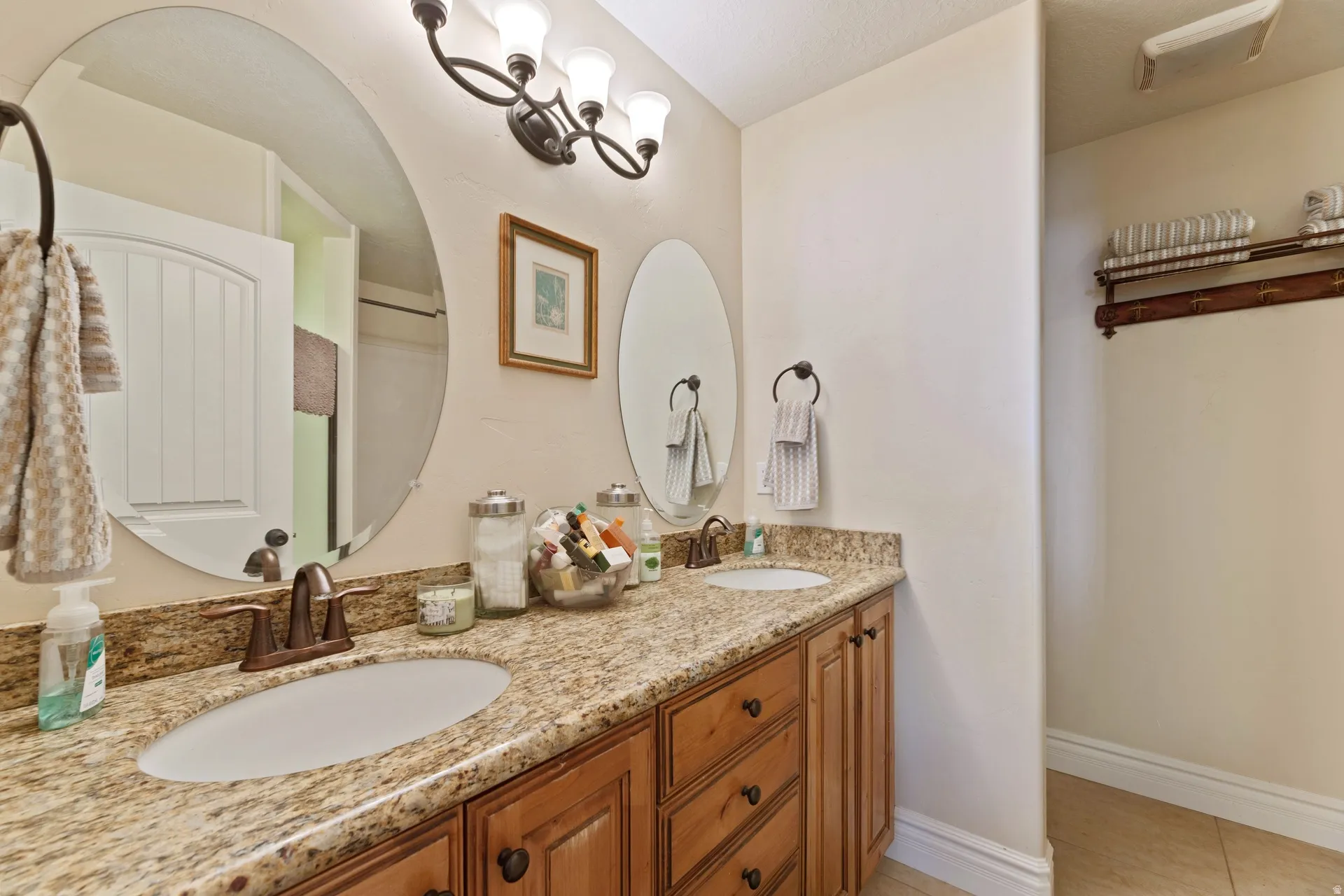 Dual oval mirrors above a granite-finish double vanity with integrated sinks