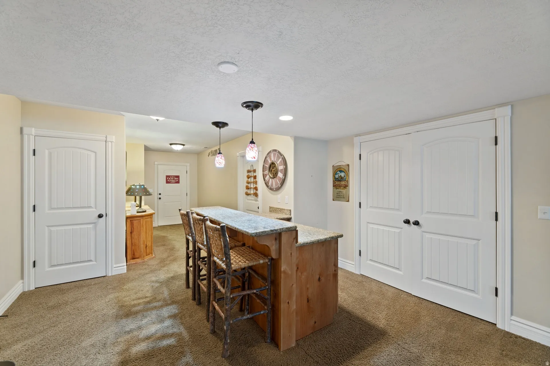 Custom bar (not sink) with granite countertop and overhead pendant lighting, large pantry closet