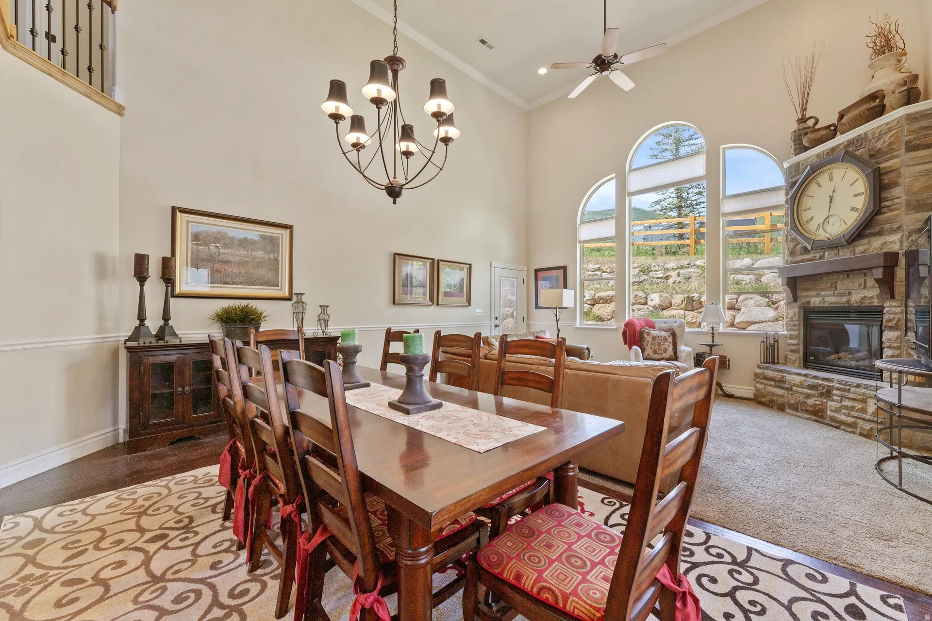 Vaulted ceilings enhance this open concept interior featuring a stone fireplace with a wood mantle, arched windows, wood-finish flooring