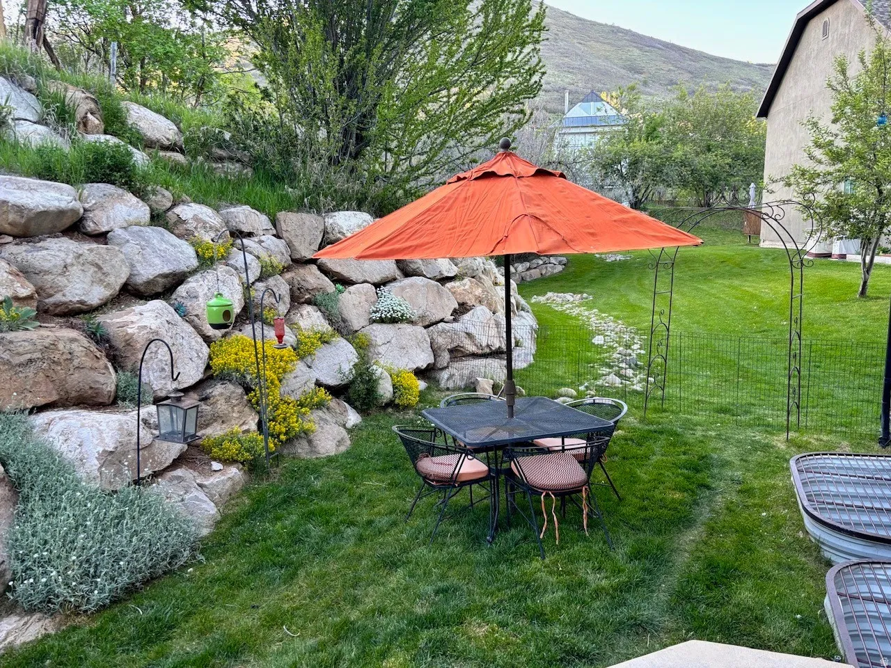 Expansive green lawn with a natural stone retaining wall