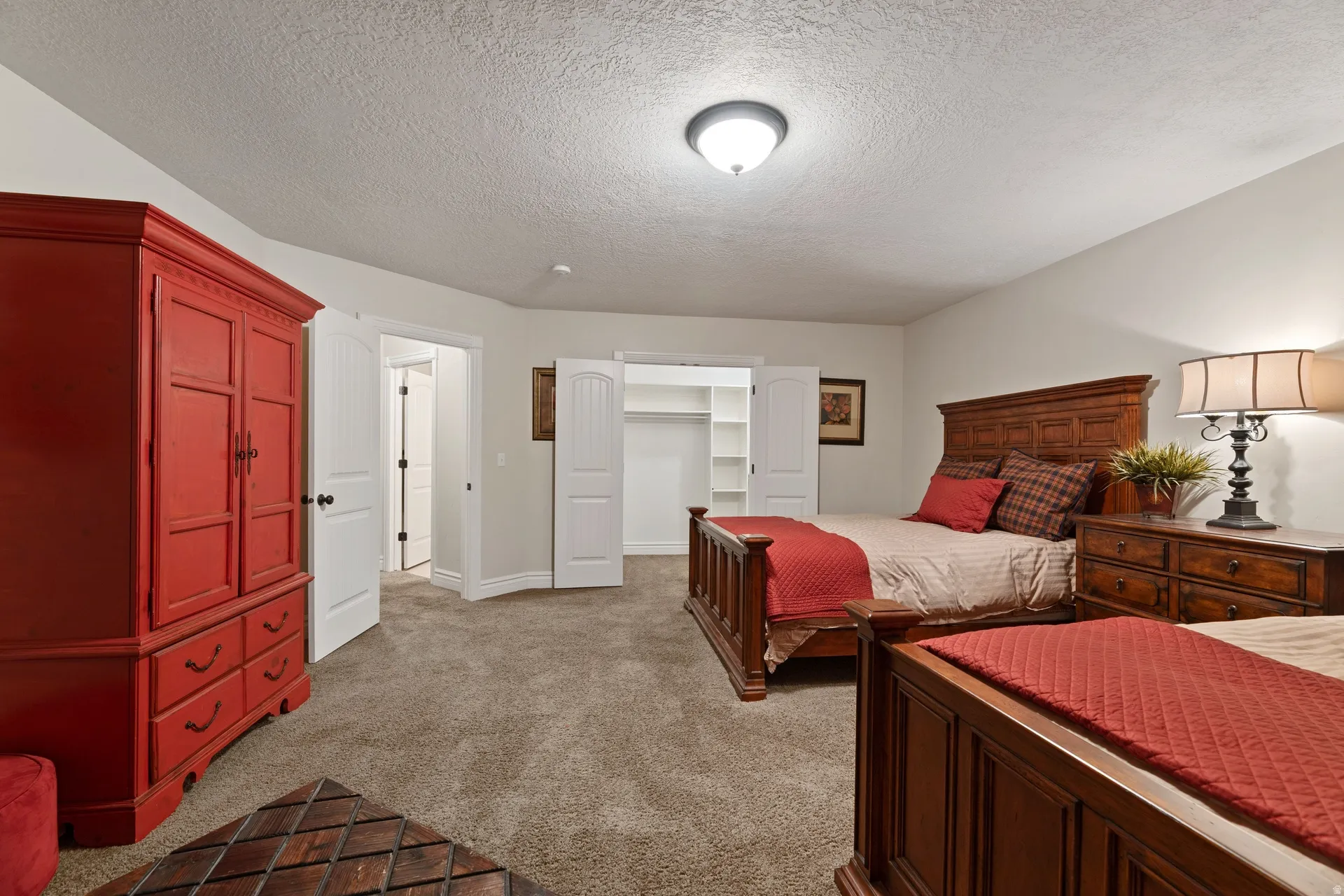 Carpeted bedroom featuring neutral wall finishes and a ceiling-mounted light fixture, walk-in closet