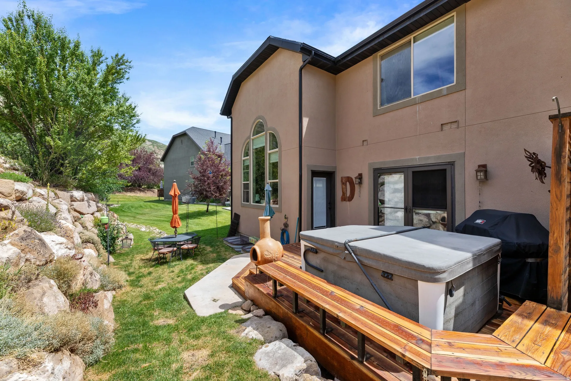 Rear exterior featuring a multi-level wooden deck, free staning private hot tub, and a stucco facade