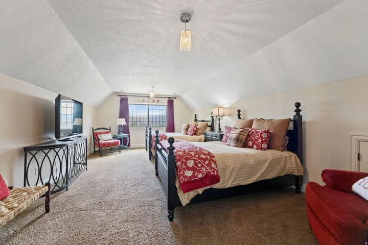 Spacious room featuring sloped ceilings, two large windows, and wall-to-wall carpeting, large walk-in closet