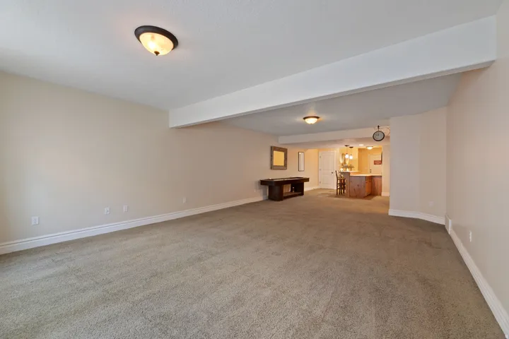Spacious open-concept room featuring neutral carpet flooring, light-toned walls, and recessed lighting