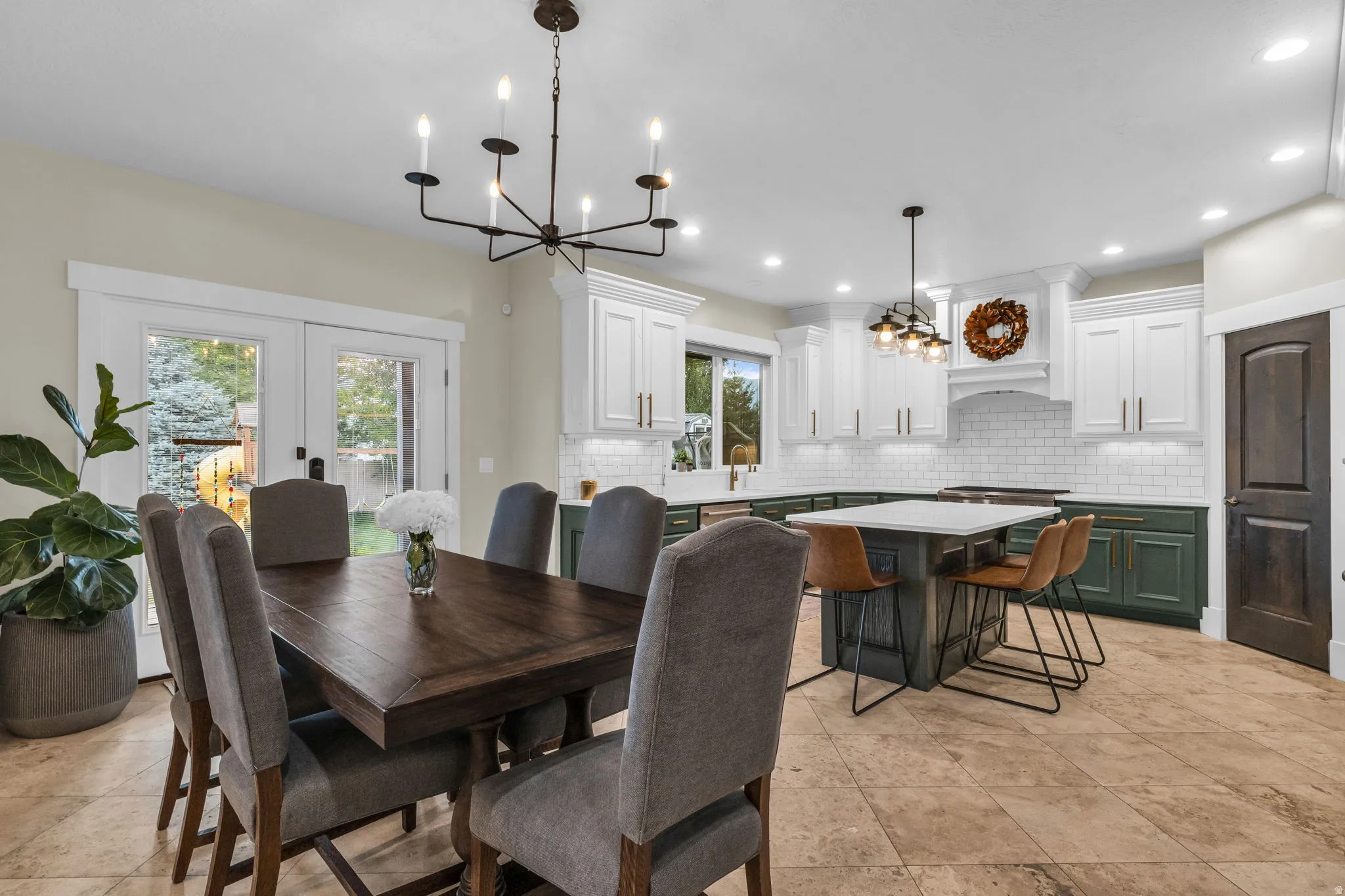 Open-concept kitchen and dining area featuring a two-tone cabinetry design, subway tile backsplash, and a central island with countertop seating