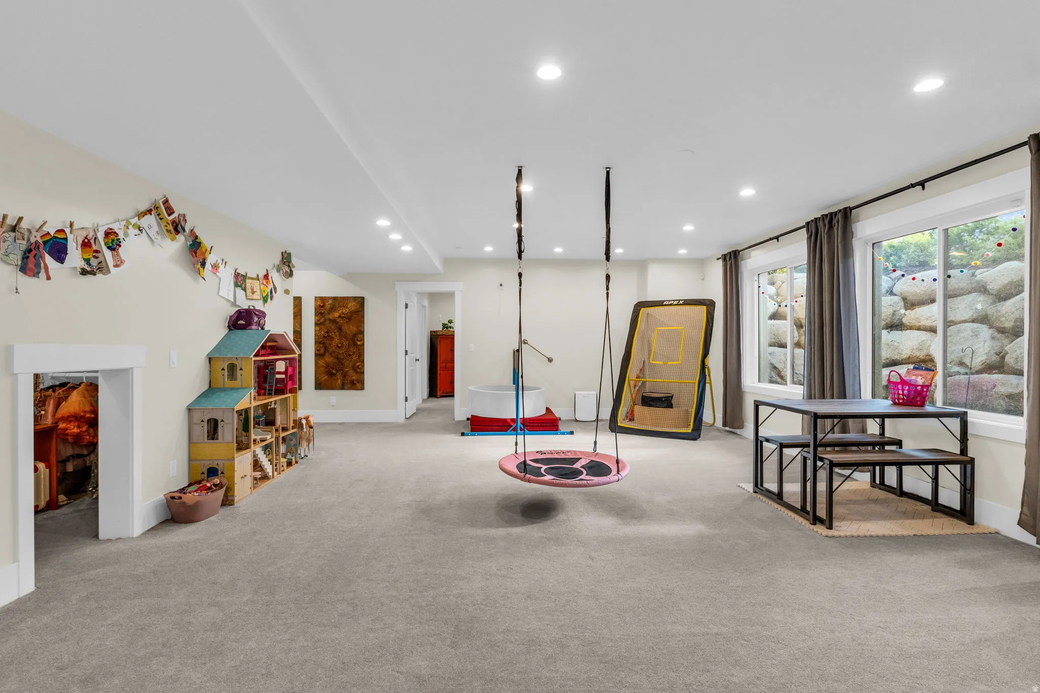 Spacious carpeted room featuring recessed lighting, multiple windows with curtains, and a white trim baseboard