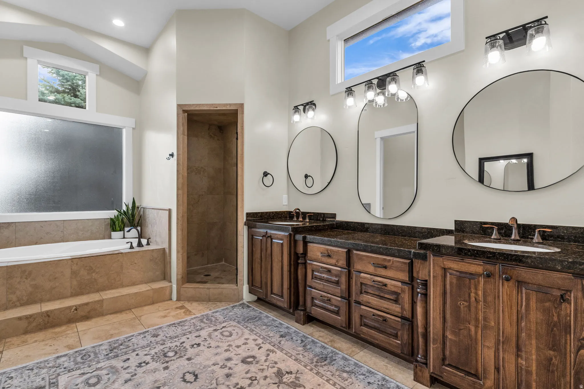 Expansive bathroom featuring a built-in soaking tub, a tiled shower enclosure, and dual vanity areas with dark wood cabinetry