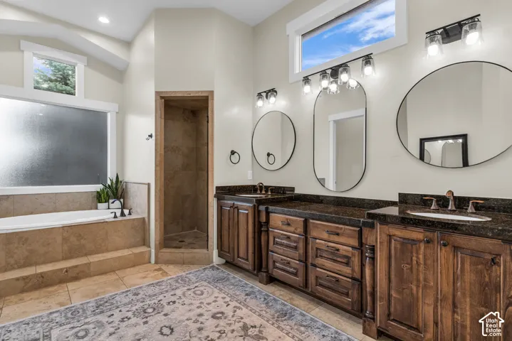 Expansive bathroom featuring a built-in soaking tub, a tiled shower enclosure, and dual vanity areas with dark wood cabinetry